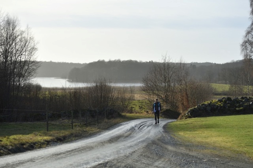 A runner on gravel with a lake in the background