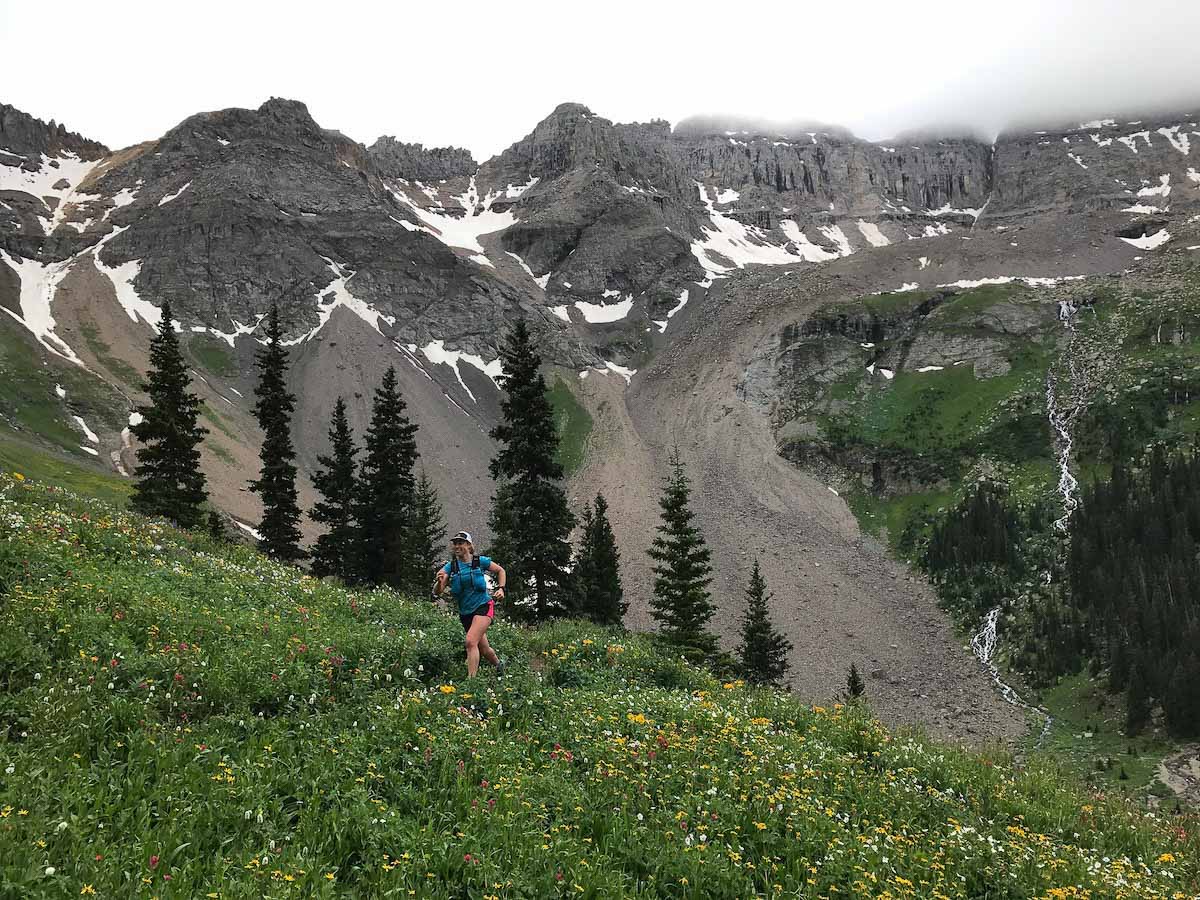 Best Running Hats - trail runner wearing hat while running in front of mountains